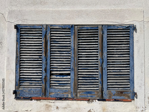 Viejas persianas azules mediteráneas en pared blanca