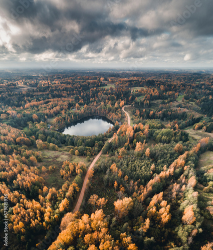 Aerial view of small gravel road, countryside, lake and colourful forest in Vorumaa, Estonia. photo