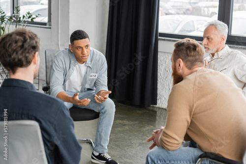 African american man with alcohol addiction sharing problem during group therapy session in rehab center. photo