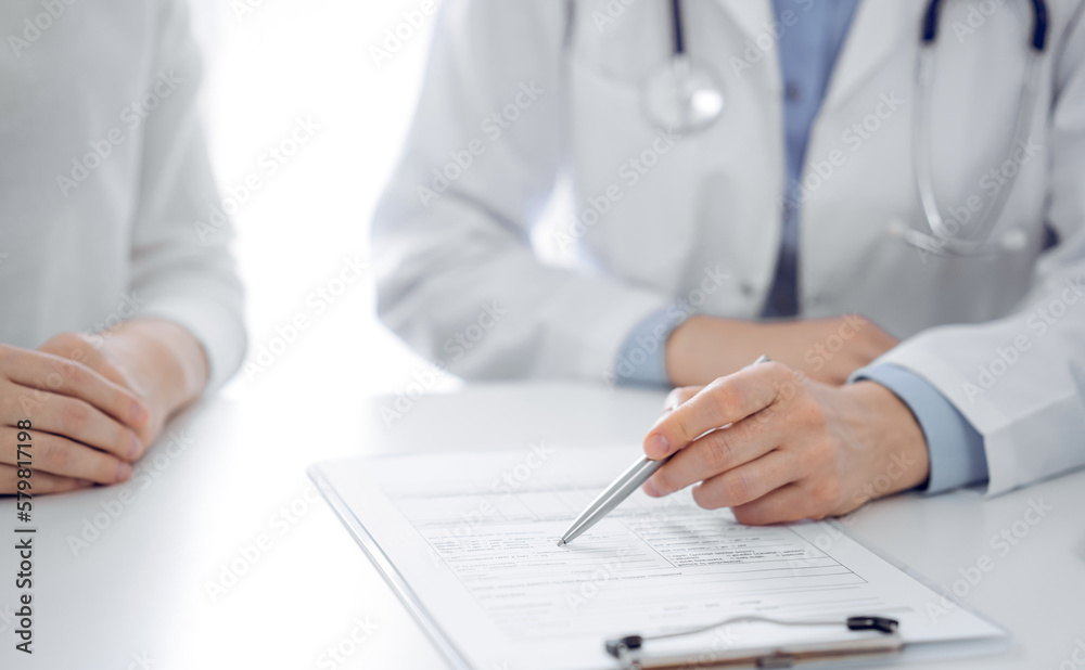 Doctor and patient discussing current health questions while sitting near of each other and using clipboard at the table in clinic, just hands closeup. Medicine concept. Doctor and patient discussing current health questions while sitting near of each other and using clipboard at the table in clinic, just hands closeup. Medicine concept.