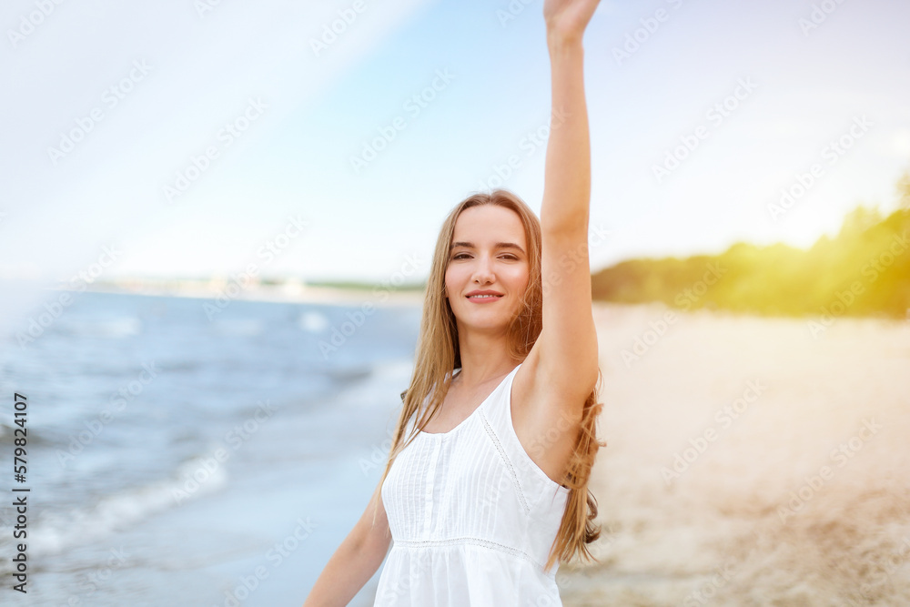 Happy smiling woman in free happiness bliss on ocean beach standing with open hands. Portrait of a multicultural female model in white summer dress enjoying nature during travel holidays vacation Happy smiling woman in free happiness bliss on ocean beach standing with open hands. Portrait of a multicultural female model in white summer dress enjoying nature during travel holidays vacation