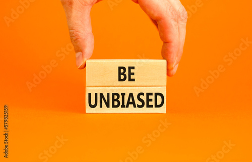 Be unbiased symbol. Concept words Be unbiased on wooden block. Beautiful orange table orange background. Businessman hand. Business psychology be unbiased concept. Copy space. photo