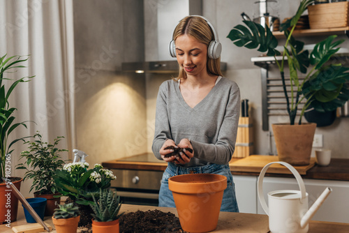 Blonde Caucasian woman puts dirt in a flowerpot