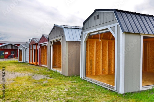 American wooden sheds with metal roof and garage sliding door style in display. Simple single-story roofed structure in a backyard or on an allotment that is used for storage, hobbies, or workshop. 