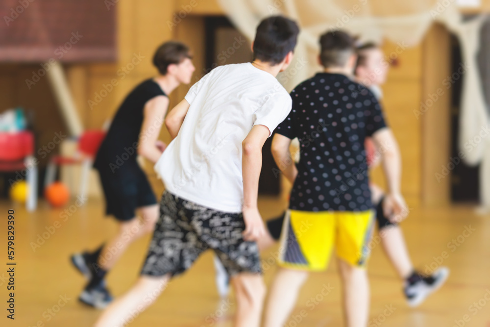 Junior teenage school team of kids children play basketball, players in the hall indoor venue court, sports team during the game, playing indoor match game on arena stadium on a wooden parquet floor Junior teenage school team of kids children play basketball, players in the hall indoor venue court, sports team during the game, playing indoor match game on arena stadium on a wooden parquet floor