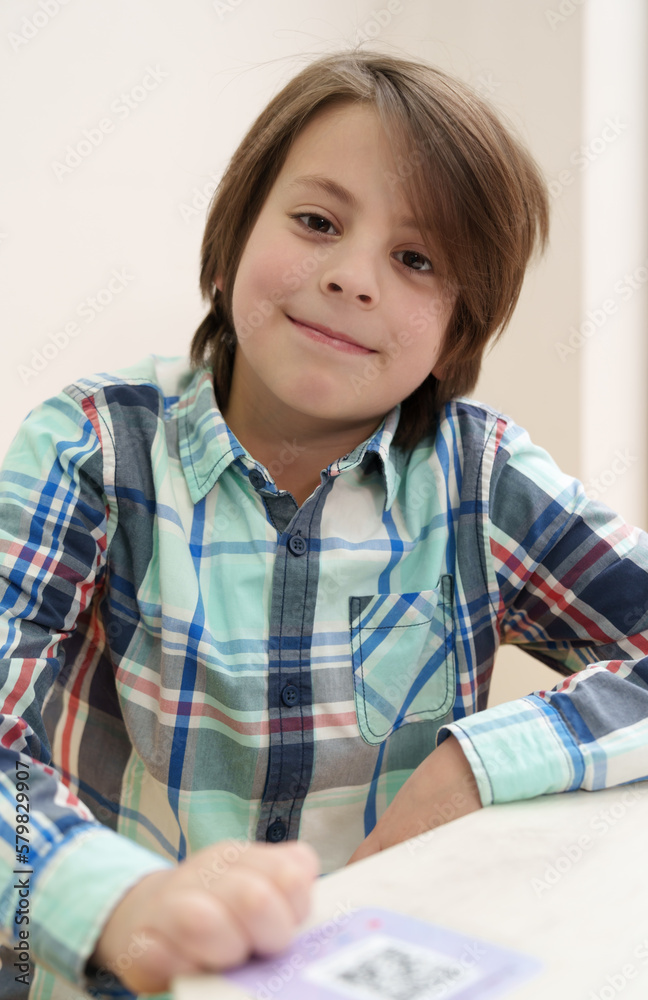 Cute white boy posing. Portrait of cheerful Ukrainian kid sitting in a cafe and waiting for his food Cute white boy posing. Portrait of cheerful Ukrainian kid sitting in a cafe and waiting for his food