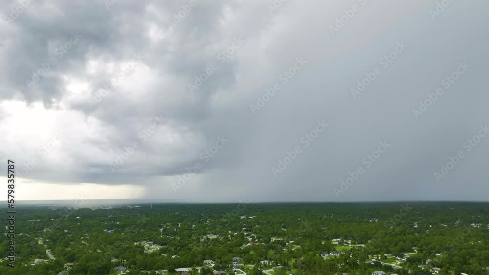 Dark stormy clouds forming on gloomy sky before heavy rainfall over suburban town area Dark stormy clouds forming on gloomy sky before heavy rainfall over suburban town area
