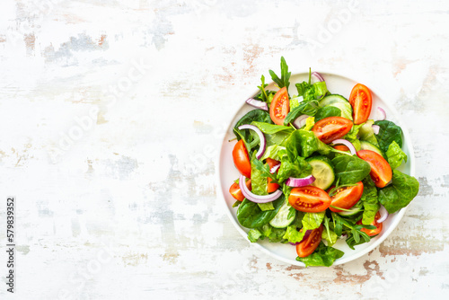 Fresh green salad with leaves and vegetables. Arugula, spinach, tomatoes and onion.