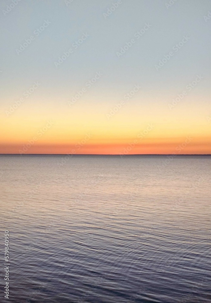 Light horizon of orange warm sky with water.