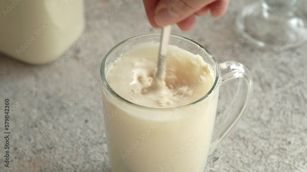 Hand stirring whey protein powder in a glass of water on a table Hand stirring whey protein powder in a glass of water on a table