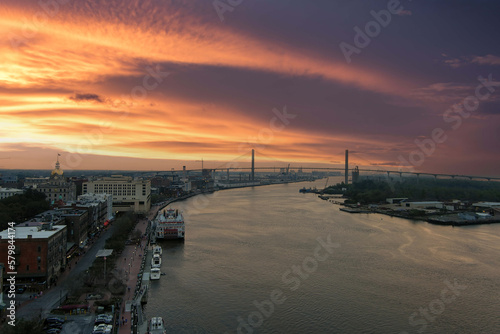 aerial shot of a gorgeous sunset over the Savannah River with Talmadge Memorial Bridge, hotels, restaurants and bars and shops docked along the river with powerful clouds at sunset in Savannah Georgia photo