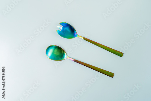 Set of iridescent metal salad spoons on a smooth surface