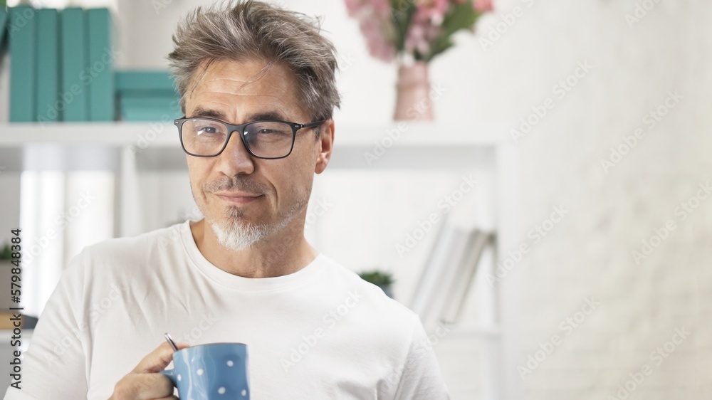 Uncombed middle aged man drinking morning coffee at home, daydreaming, smiling. Uncombed middle aged man drinking morning coffee at home, daydreaming, smiling.