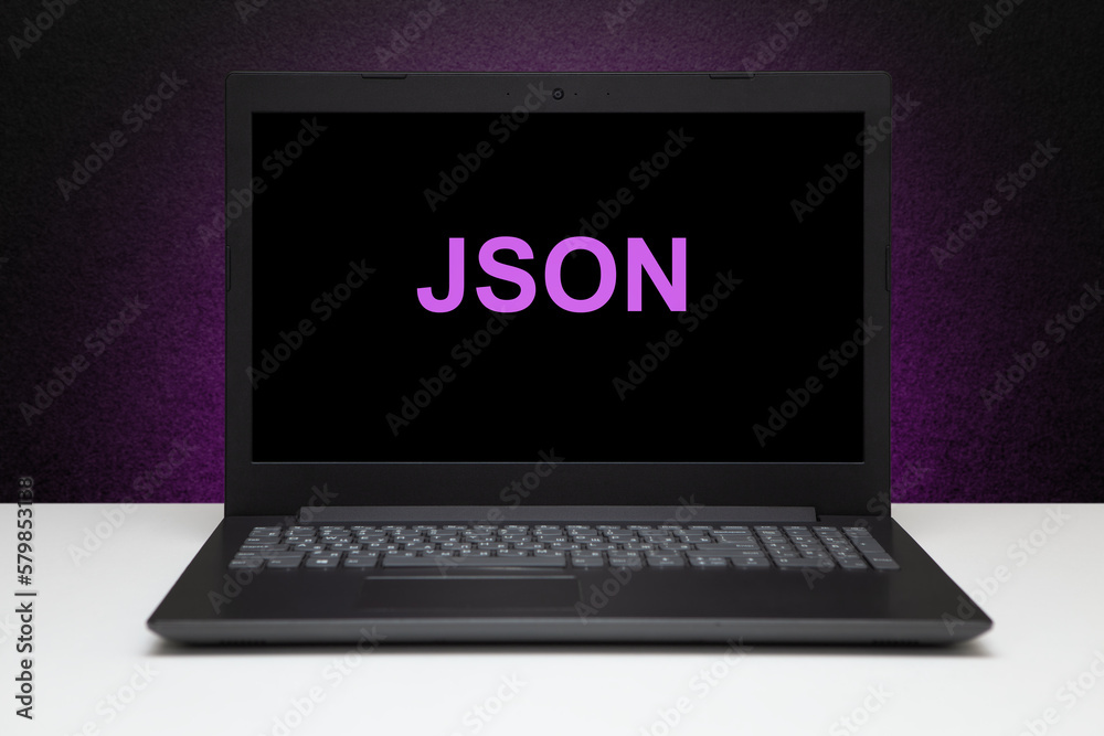 JSON text on laptop screen on textured black background with purple light. Technology concept. JSON text on laptop screen on textured black background with purple light. Technology concept.