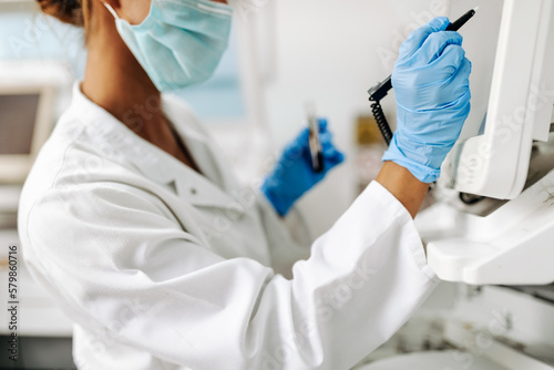 Female scientist or technician with a face protective mask working in modern laboratory.