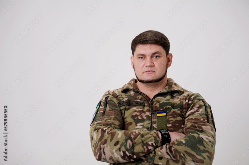 portrait of male in camouflage coat on gray background Studio shot of young bearded ukrainian man Young hispanic man