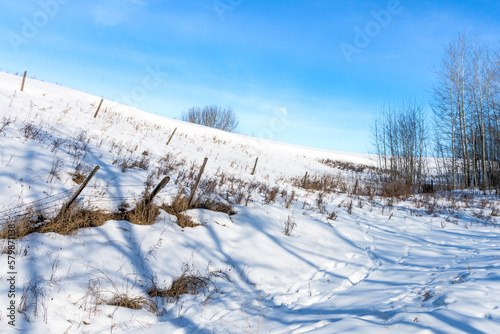 Farm field edge ravine with barbed fence and blues sky background in winter season