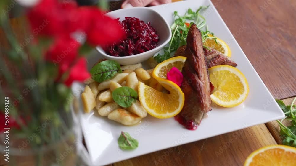 Duck fillet served on a white plate with orange slices mint leaves and potato dumplings Duck fillet served on a white plate with orange slices mint leaves and potato dumplings