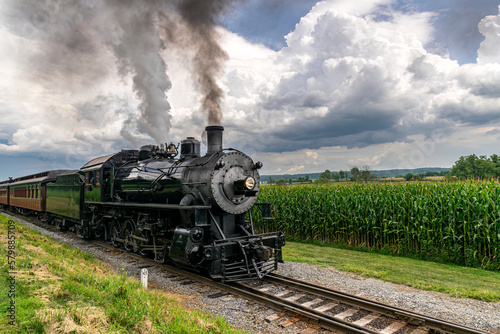 A Steam Passenger Train Passing Corn Fields and Blowing Smoke on a Sunny Summer Day