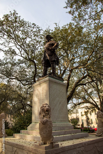 A statue of General James Edward Oglethorpe at Franklin Square with lush green weeping willow trees, plants and grass in Savannah Georgia USA photo
