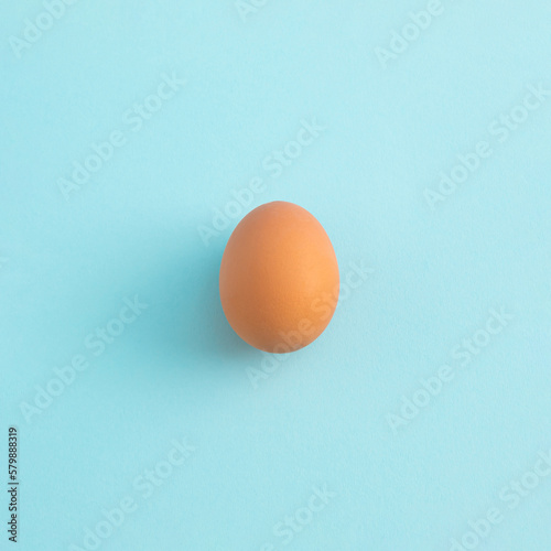 Uncooked egg on pastel blue background. Minimal food concept with copy space. Top view, flat lay.