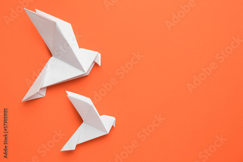 Beautiful white origami birds on orange background, flat lay. Space for text