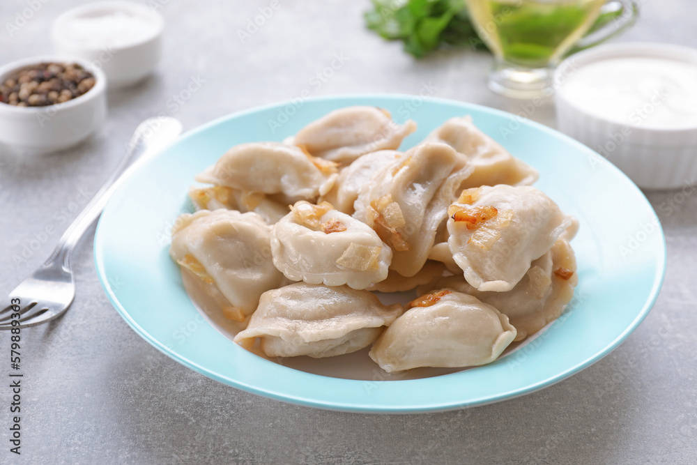 Delicious dumplings (varenyky) with potatoes and onion served on grey table Delicious dumplings (varenyky) with potatoes and onion served on grey table