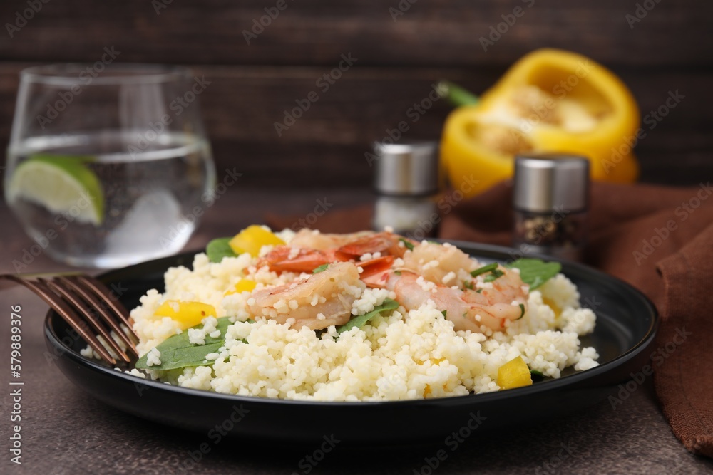 Tasty couscous with shrimps, bell pepper and basil on brown textured table, closeup Tasty couscous with shrimps, bell pepper and basil on brown textured table, closeup