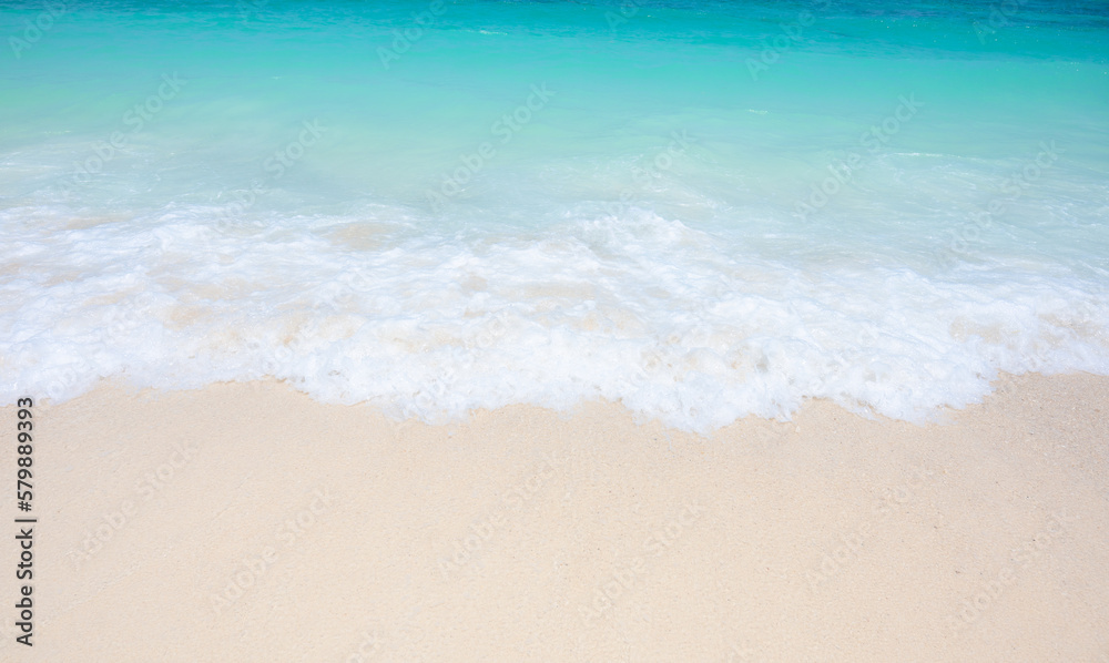 Light blue sea waves on clean sandy beach.