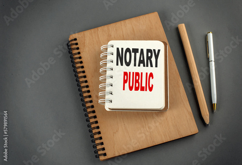 NOTARY PUBLIC text on notebook with pen and pencil on grey background