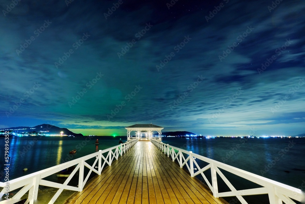 Obraz premium The night view of the sea coast has a long bridge.