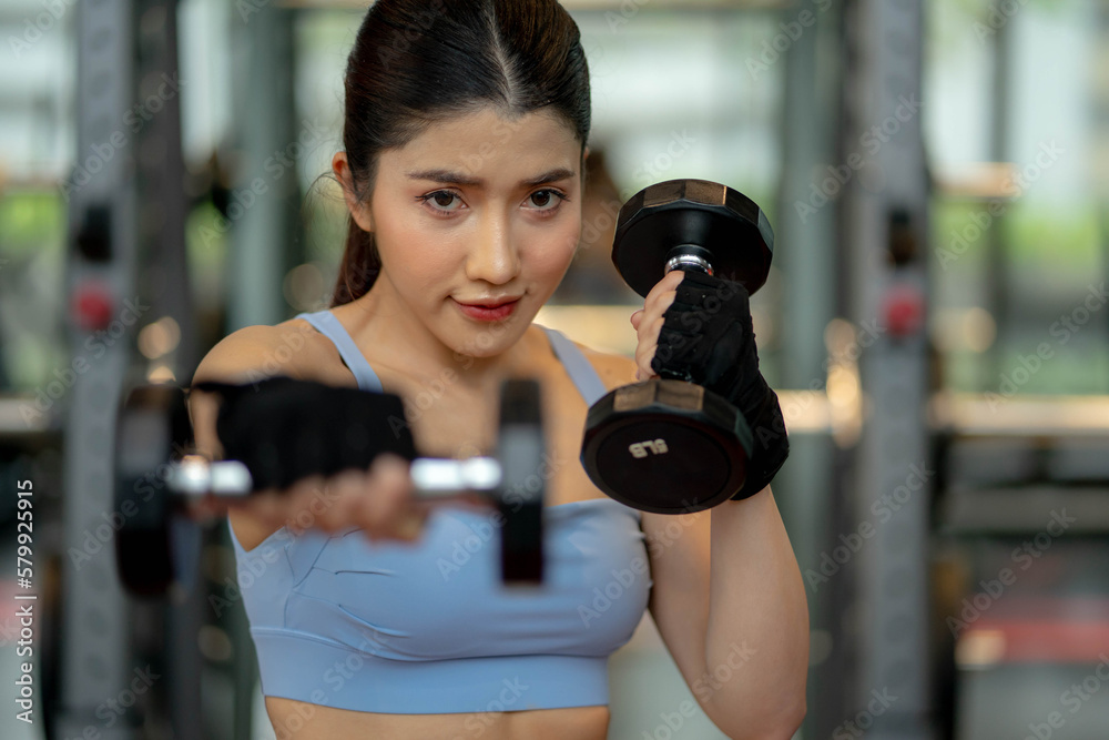 Beautiful young girl and doing exercises with dumbbells Beautiful young girl and doing exercises with dumbbells