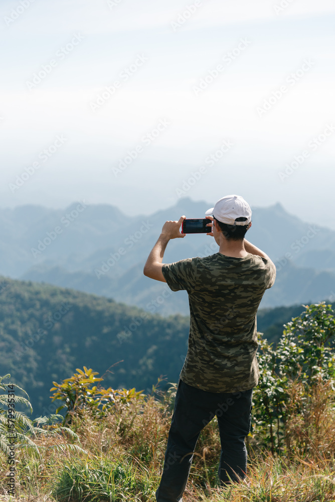 Male traveler take photo top of mountain when trekking in national park of Thailand