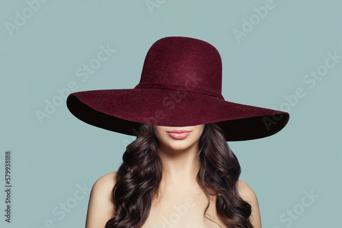 Nice woman in wide red hat on blue background