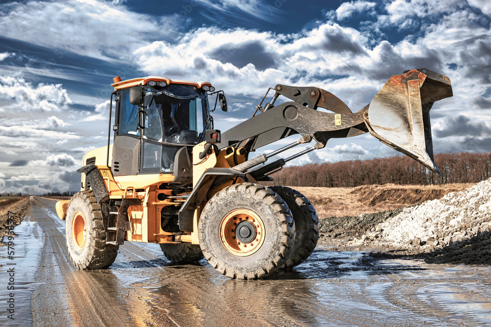 Fototapeta premium Powerful wheel loader or bulldozer working on a quarry or construction site. Earthworks in construction. Powerful modern equipment for earthworks.