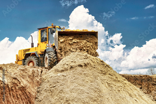 Powerful wheel loader or bulldozer working on a quarry or construction site. Loader with a full bucket of sand. Powerful modern equipment for earthworks. photo