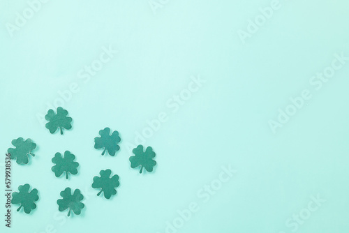 Happy St. Patrick's Day decoration background. Flat lay of cutting paper clover leaves festive decor, shamrocks leaves holiday symbol with copy space on colour background, Banner greeting card concept
