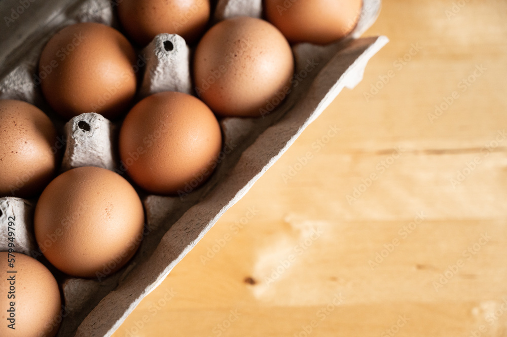 Close up of a carton of brown organic eggs on wood kitchen table Close up of a carton of brown organic eggs on wood kitchen table