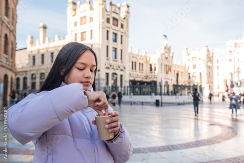 Girl with paper chocolate cup in the city centre dipping something.