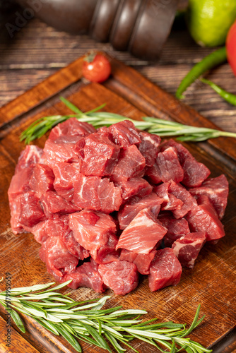Raw fresh beef or lamb cubes. Diced red beef meat on a wood serving board. Raw casserole or stewing beef diced