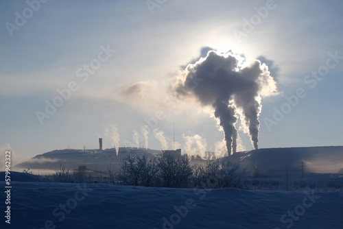 Iron ore mine in Kiruna in sunny winter scenery. Clouds of smoke illuminated by the sun. Sweden, Arctic Circle, Swedish Lapland