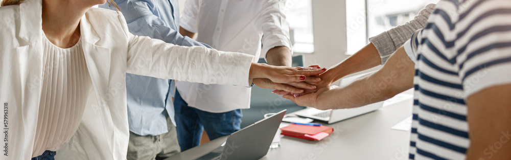 Happy group of multi ethnic coworkers stacked hands together as concept of corporate unity Happy group of multi ethnic coworkers stacked hands together as concept of corporate unity