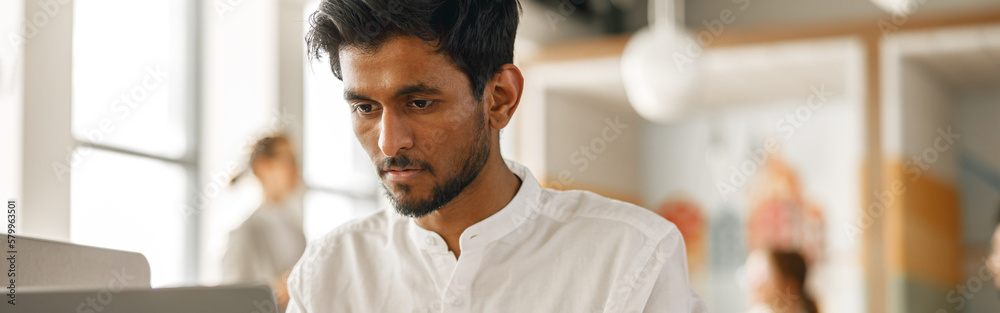 Obraz premium Businessman working laptop while sitting in modern office on colleagues background
