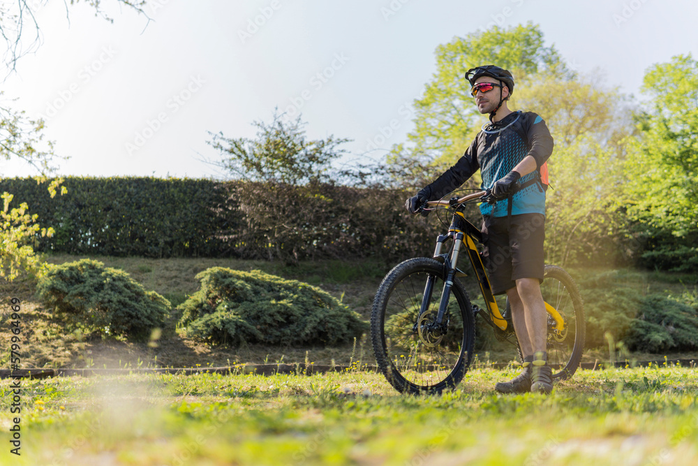 Full length of young man with mountain bike standing on field at park Full length of young man with mountain bike standing on field at park
