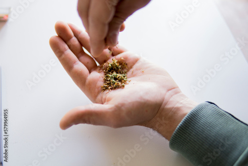 Close-up of hands mixing marijuana joints and tobacco product over table