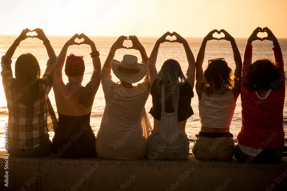 Group Of Women Sitting Against A Golden Sunset And Doing Heart Symbol 