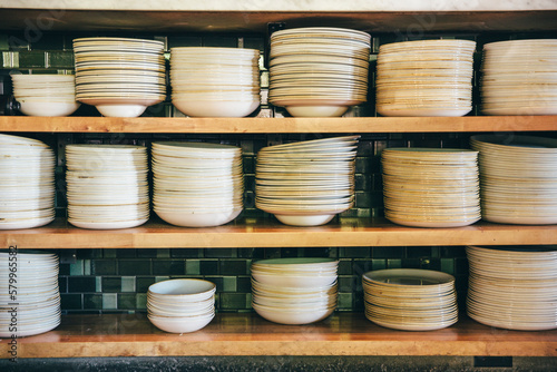 Close-up of plates and bowls on shelves at commercial kitchen photo