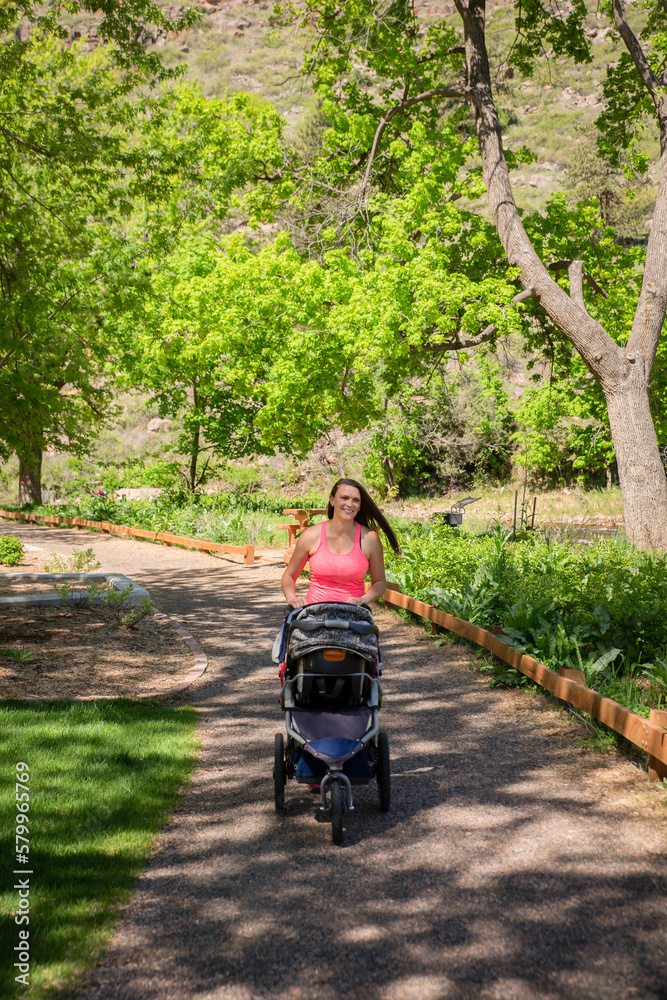 Woman with baby stroller walking on footpath at park during summer