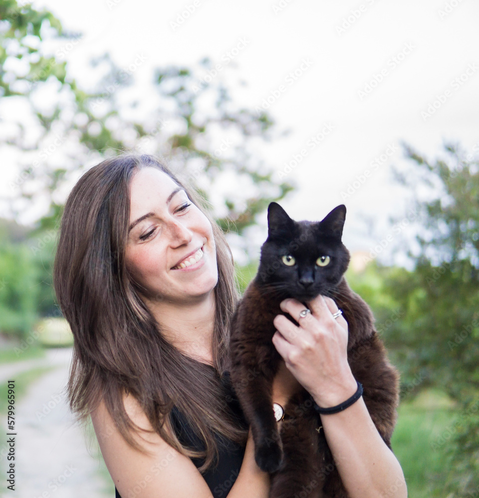 Happy woman carrying cat while standing against clear sky at park Happy woman carrying cat while standing against clear sky at park