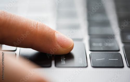 Cropped finger of boy touching laptop computer's keyboard